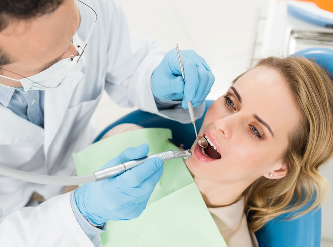 врач лечит зубы женщине во время месячных
